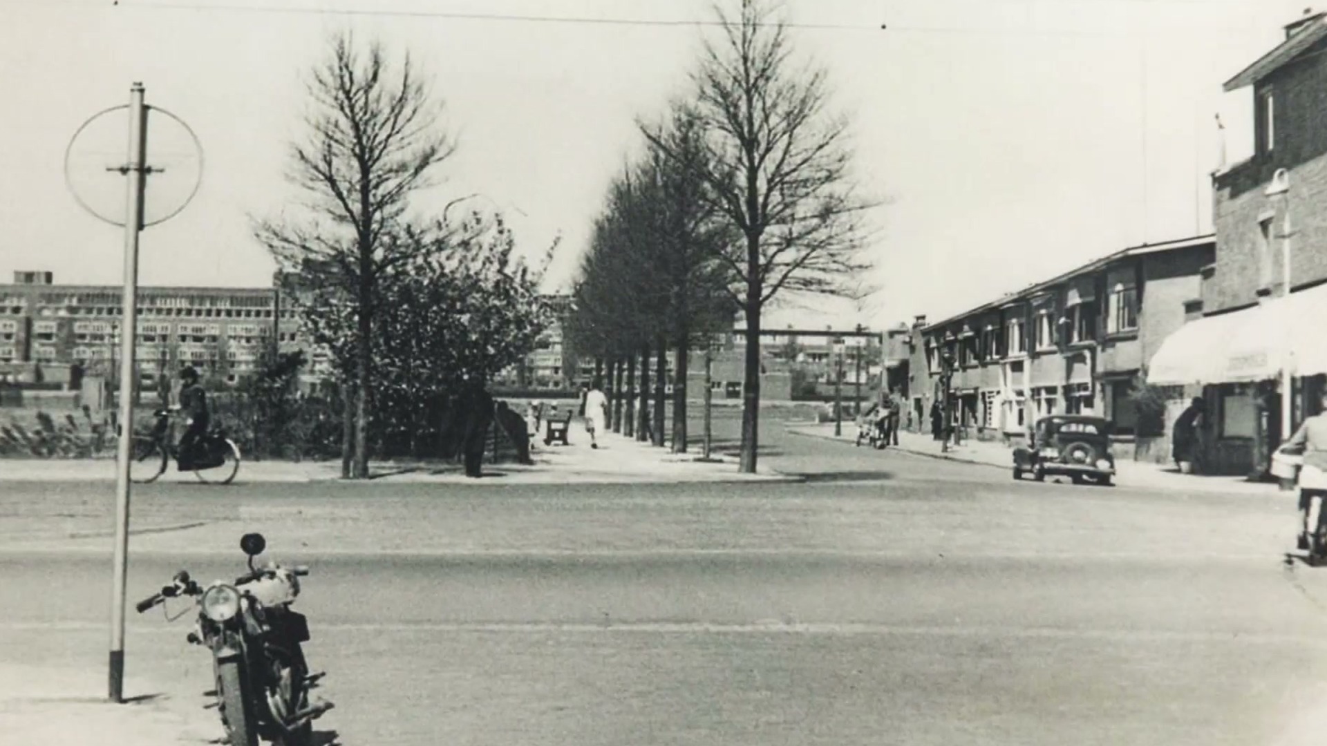 Archieffoto van de Laan van Meerdervoort: een brede laan met kale bomen, fietsers en een enkele auto, met een geparkeerde motor op de voorgrond.
